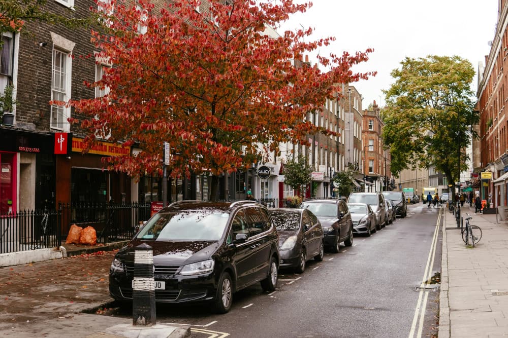 London residential street with parked cars and moving vans